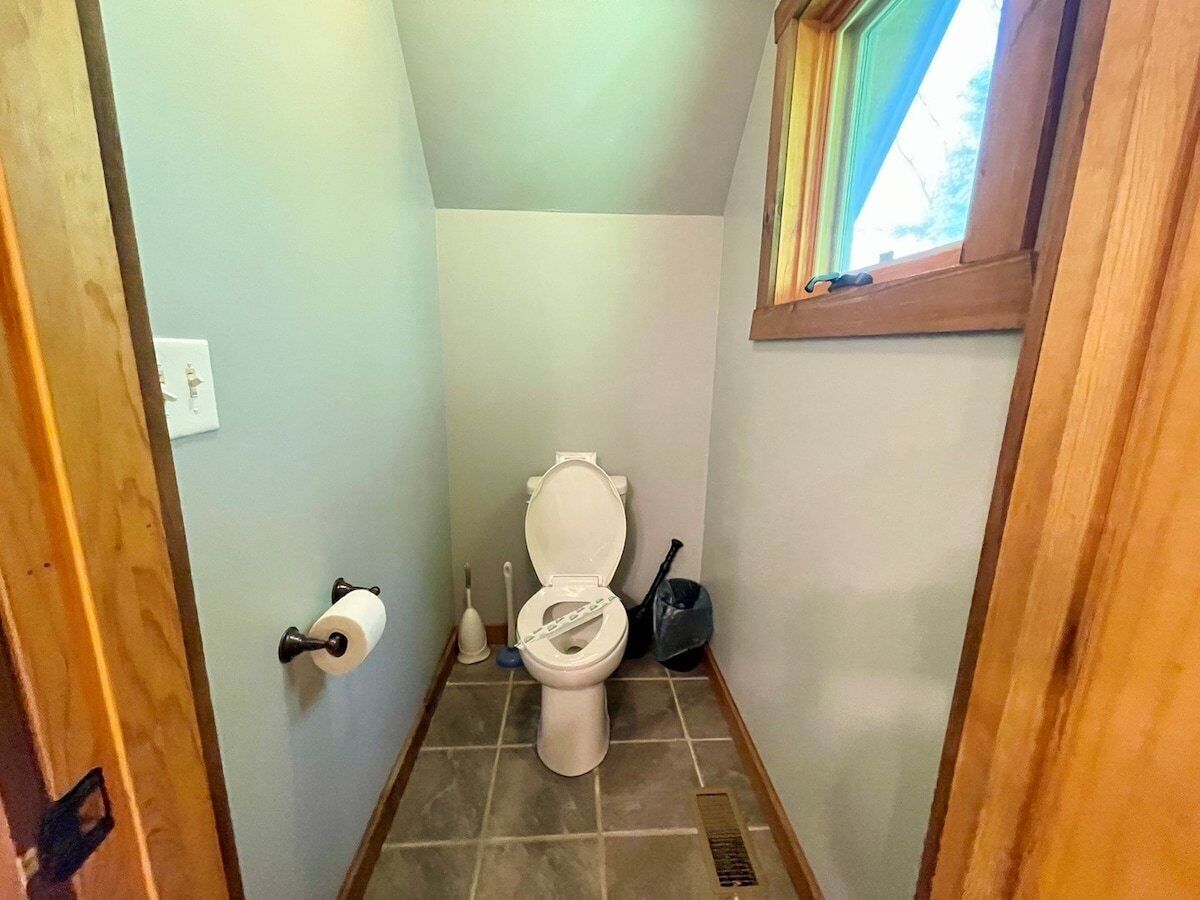 Une petite salle de bain comprenant des toilettes, un porte-rouleau de papier toilette, une ventouse et une poubelle.