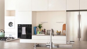 A modern kitchen with a stainless steel sink, a built-in oven, a refrigerator, and a gas stove. - Spacious & Stylish 3BR Apt w Beautiful Street View (Tel Aviv)