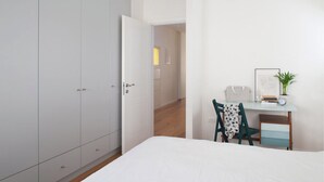 A bedroom with a bed, a desk with a chair, a wardrobe, and a door leading to another room. - Spacious & Stylish 3BR Apt w Beautiful Street View (Tel Aviv)