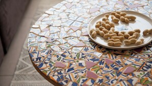 A round table with a mosaic tile design and a plate of peanuts. - Spacious & Stylish 3BR Apt w Beautiful Street View (Tel Aviv)