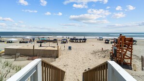 Een strand met parasols, ligbedden en een uitkijktoren.