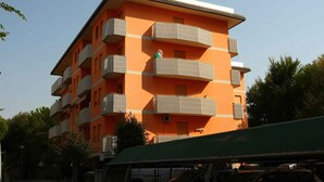 Um edifício de vários andares com varandas, um telhado plano e céu limpo.