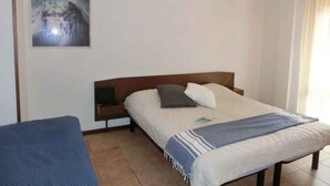 Um quarto com uma cama, uma mesa de cabeceira, uma cadeira e um quadro na parede.