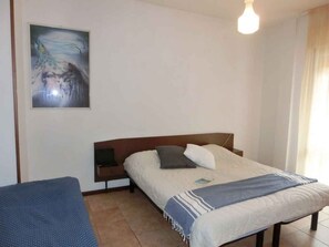A bedroom with a bed, a bedside table, a chair, and a painting on the wall.