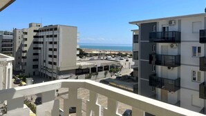 A view of a coastal residential area with modern apartment buildings, a parking lot, and a beach in the background. - Holiday apartment near the beach (Bibione)