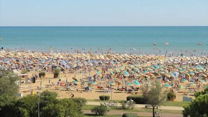 A crowded beach with numerous umbrellas and sun loungers. - Holiday apartment near the beach (Bibione)