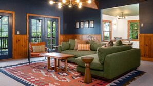 Ein gemütliches Wohnzimmer mit einem grünen Sofa, Holzelementen und einem gemusterten Teppich.
