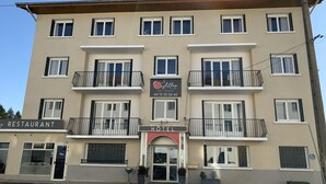 A multi-story building with a restaurant and hotel sign. - Le Costellan (Dagneux)