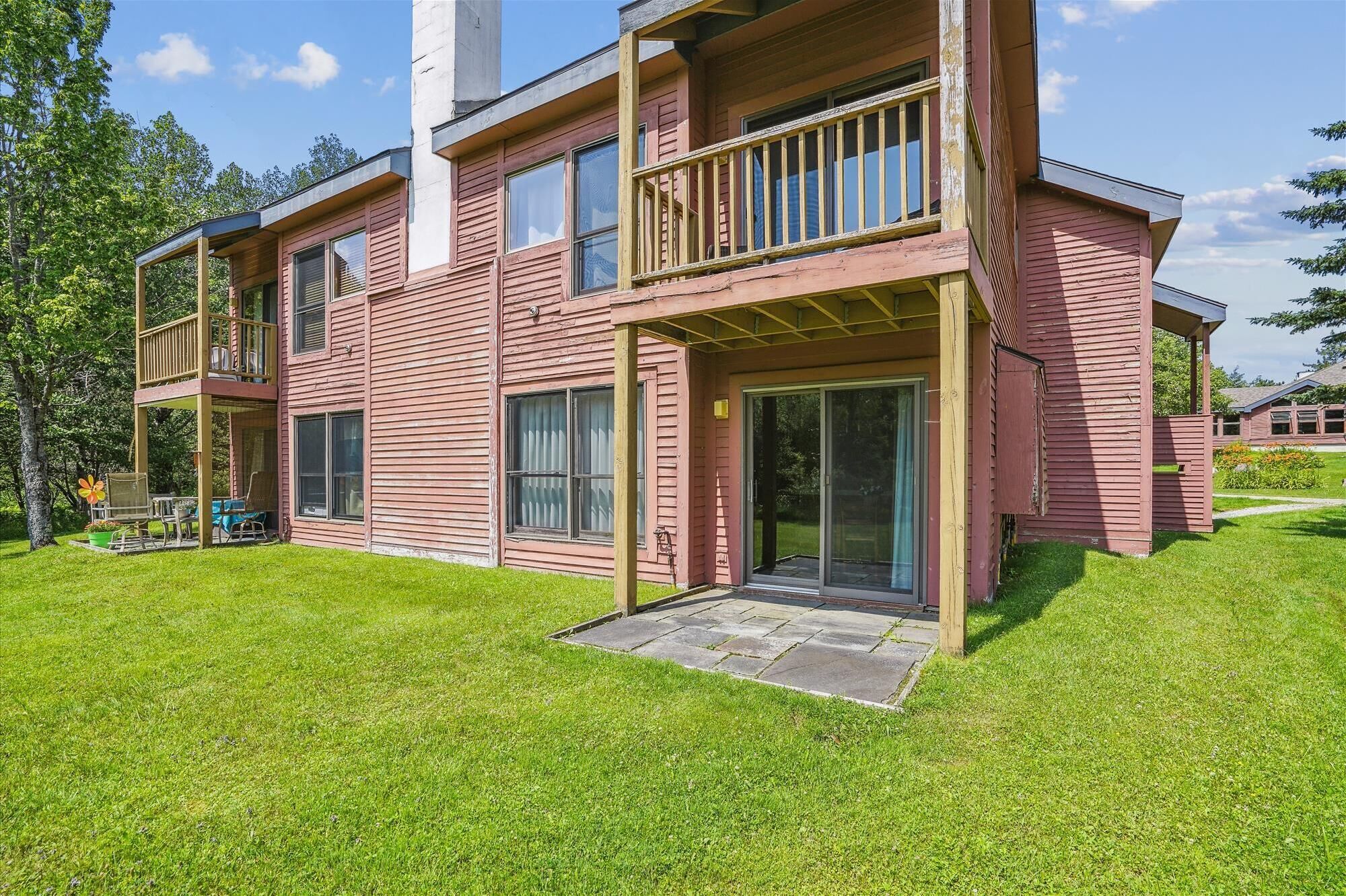 A two-story house with a balcony, large windows, and a well-maintained lawn.