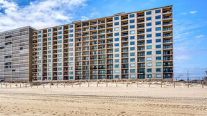 Ein Hochhaus mit zahlreichen Balkonen und einem Sandstrand im Vordergrund.