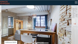 A cozy room with a wooden dining table, chairs, and a stone wall. - Pause Café (Annecy)