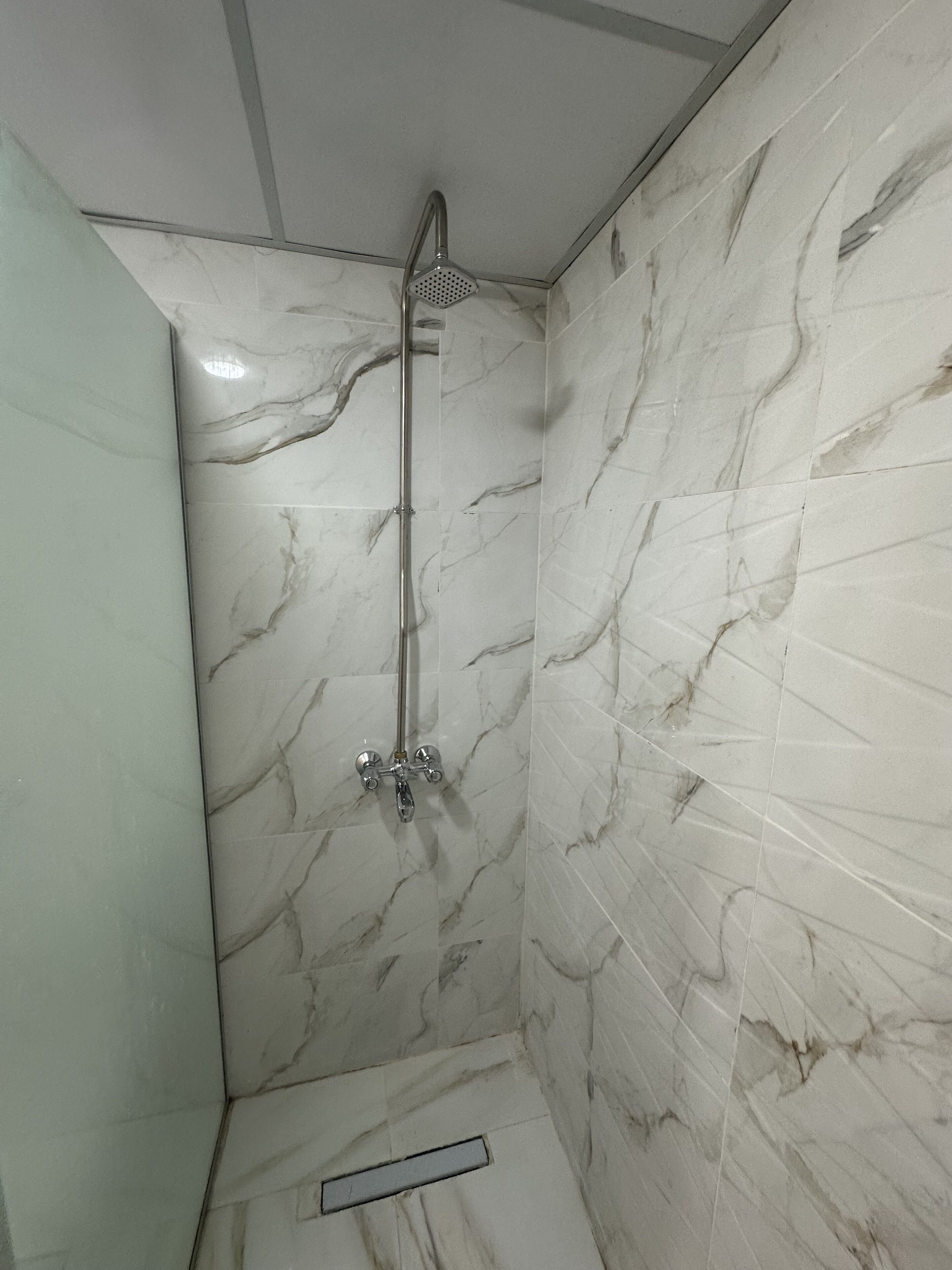 Un baño con paredes de mármol y ducha.