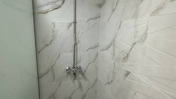 Un baño con paredes de mármol y ducha.
