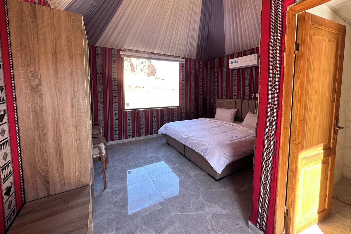 A room with a bed, a window, a door, and patterned walls.