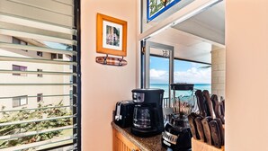Una cocina con cafetera, bloque de cuchillos y un cuadro en la pared.