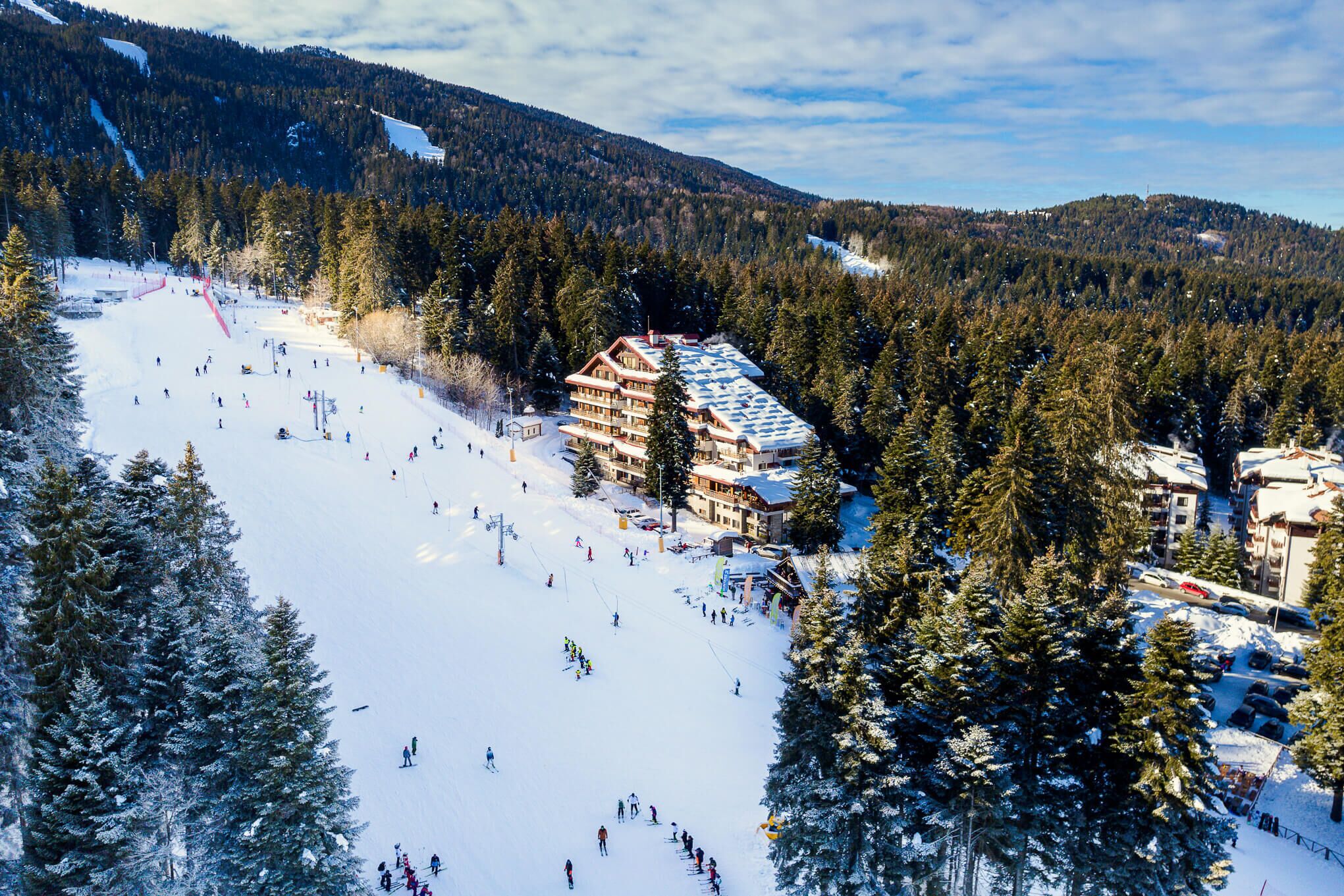 A ski resort with a large lodge, multiple ski slopes, and dense forested mountains.