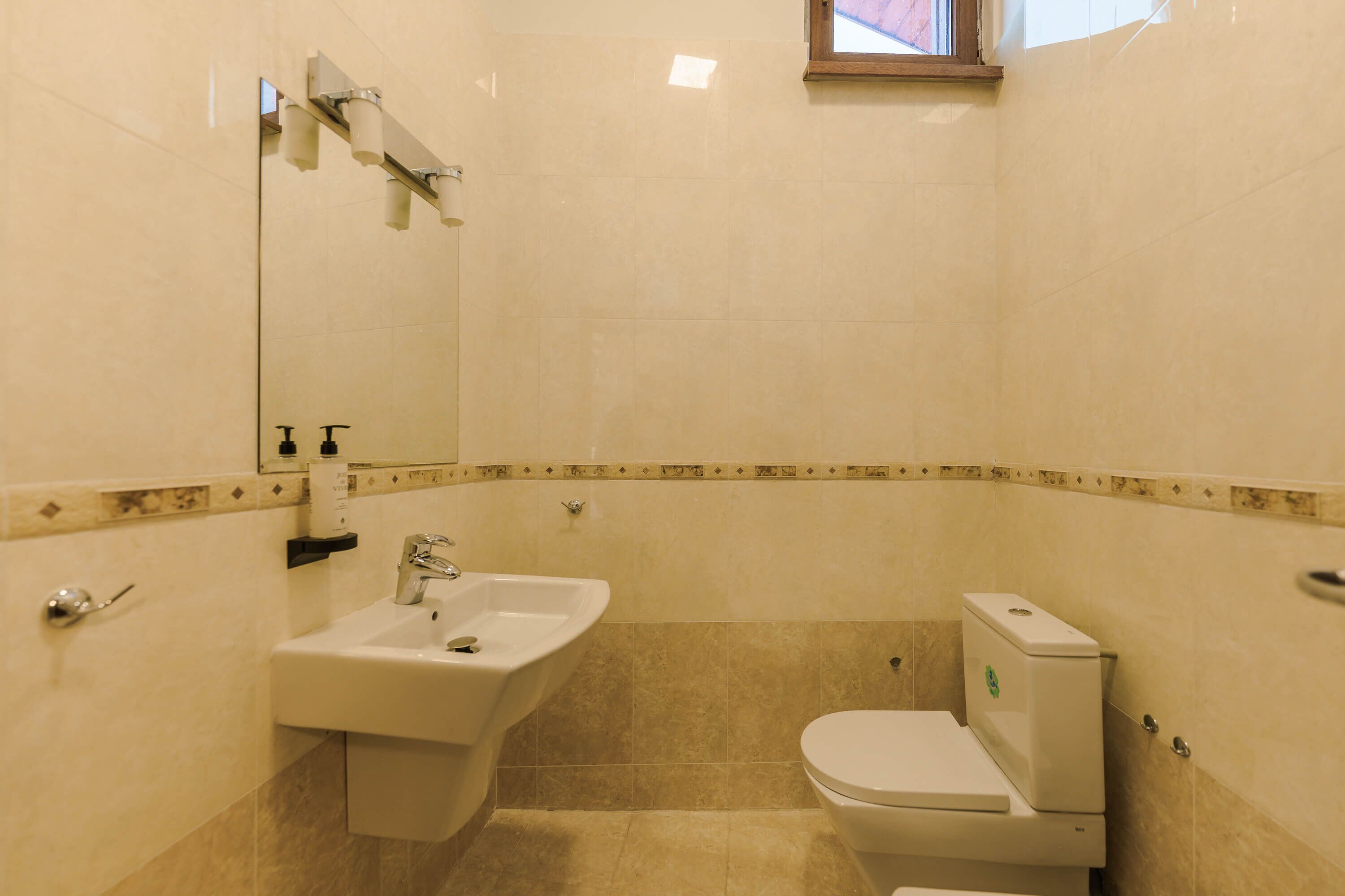 A bathroom with a sink, toilet, and a mirror.