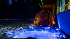 Un jacuzzi de diseño circular, rodeado por una zona cubierta con luces colgantes.