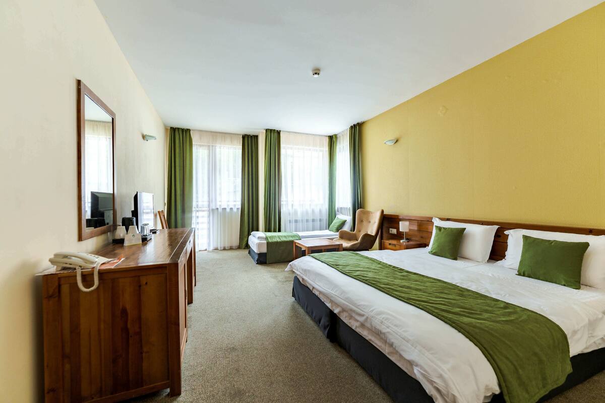Una habitación de hotel con una cama grande, un escritorio con teléfono, una silla y una pequeña mesa.