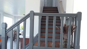 A staircase with a grey railing and wooden steps, leading to an upper floor. -  The house right on the water with direct access to the beach. (Ouistreham)