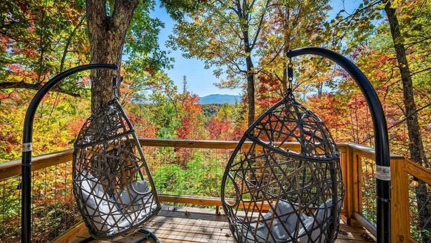A wooden deck with two wicker chairs overlooking a forest with autumn foliage. - Secluded cabin w views! Game Room & FREE TIX! (Sevierville)