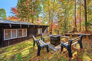 A cabin with a deck, outdoor seating, and a fire pit.