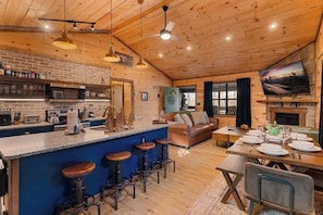 A rustic cabin interior with a kitchen, dining area, and living space.