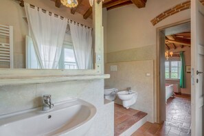 A bathroom with a large sink, two toilets, and a shower area.