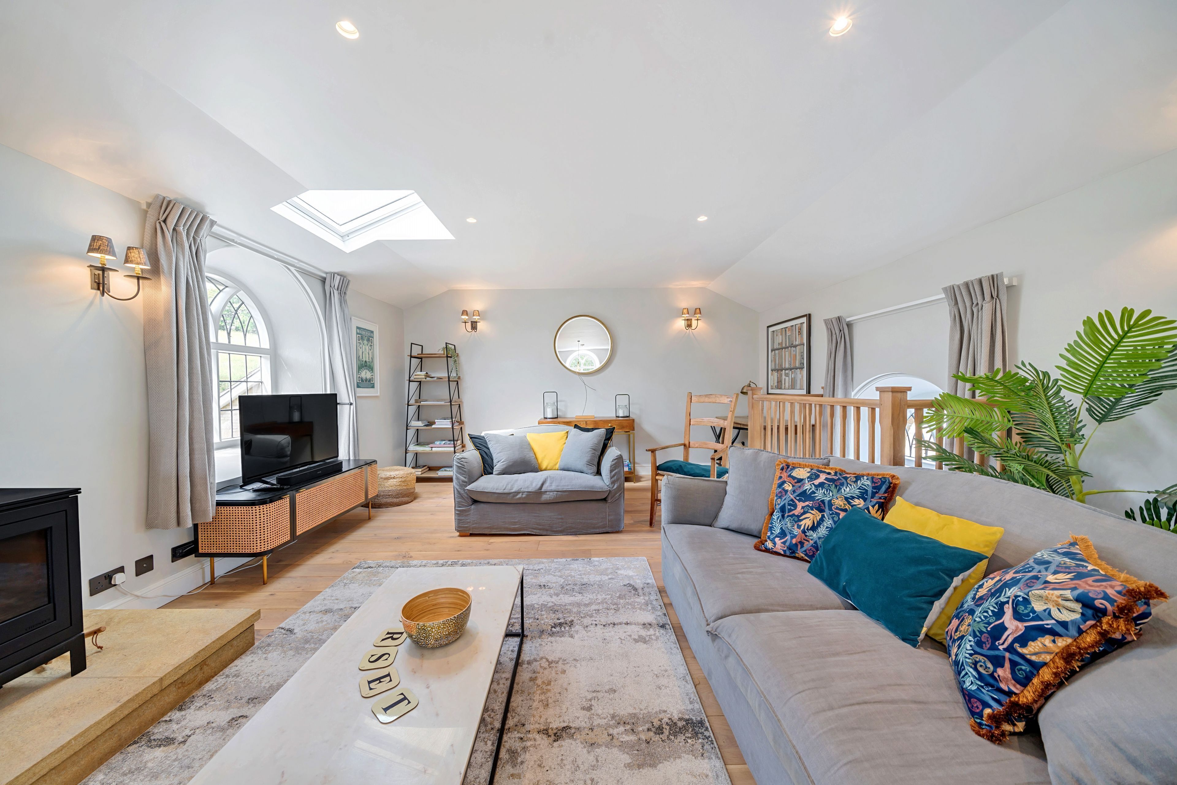 A living room with a sofa, television, and a skylight.