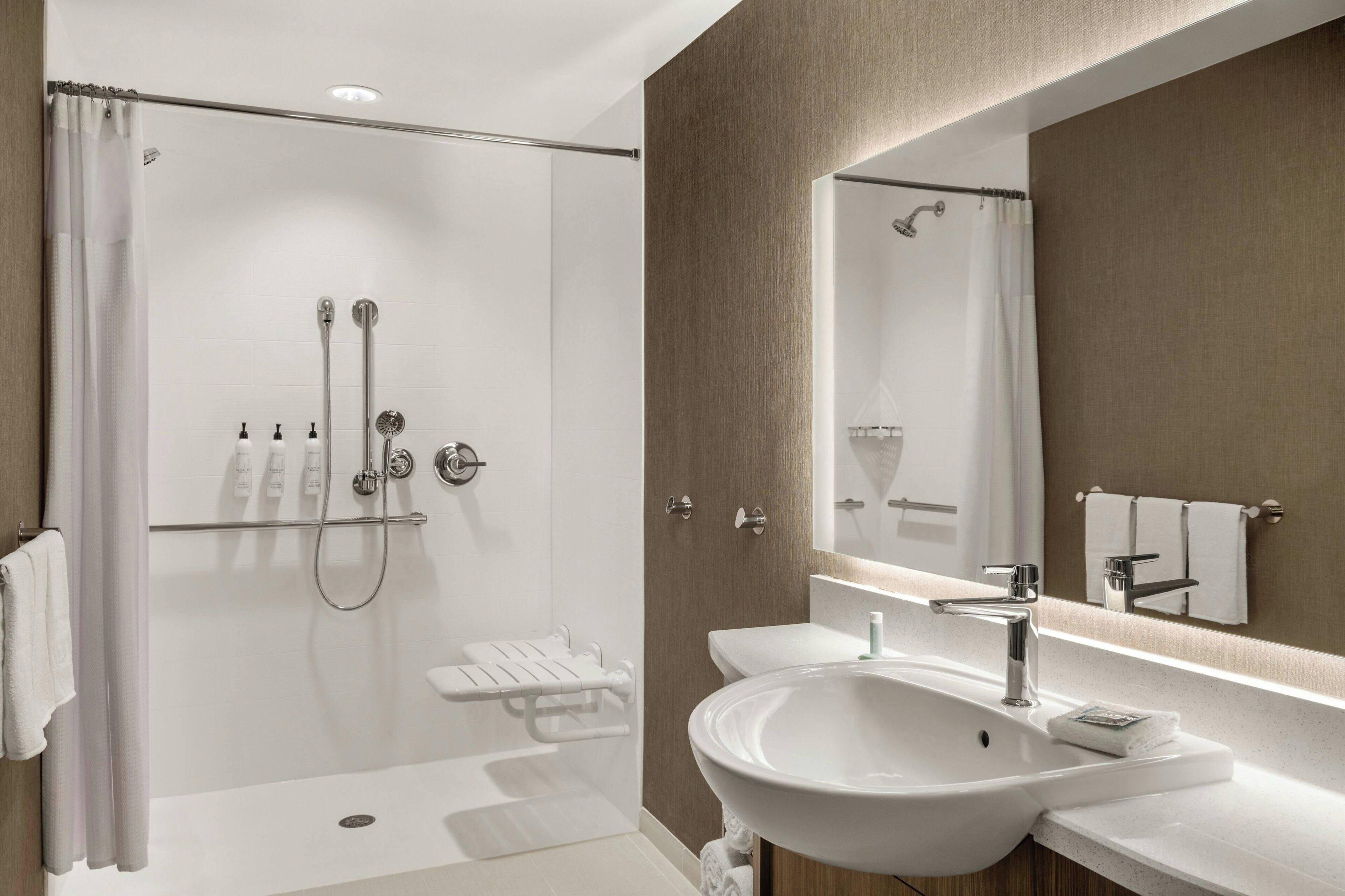 A modern bathroom with a walk-in shower, a large mirror, and a dual sink vanity.
