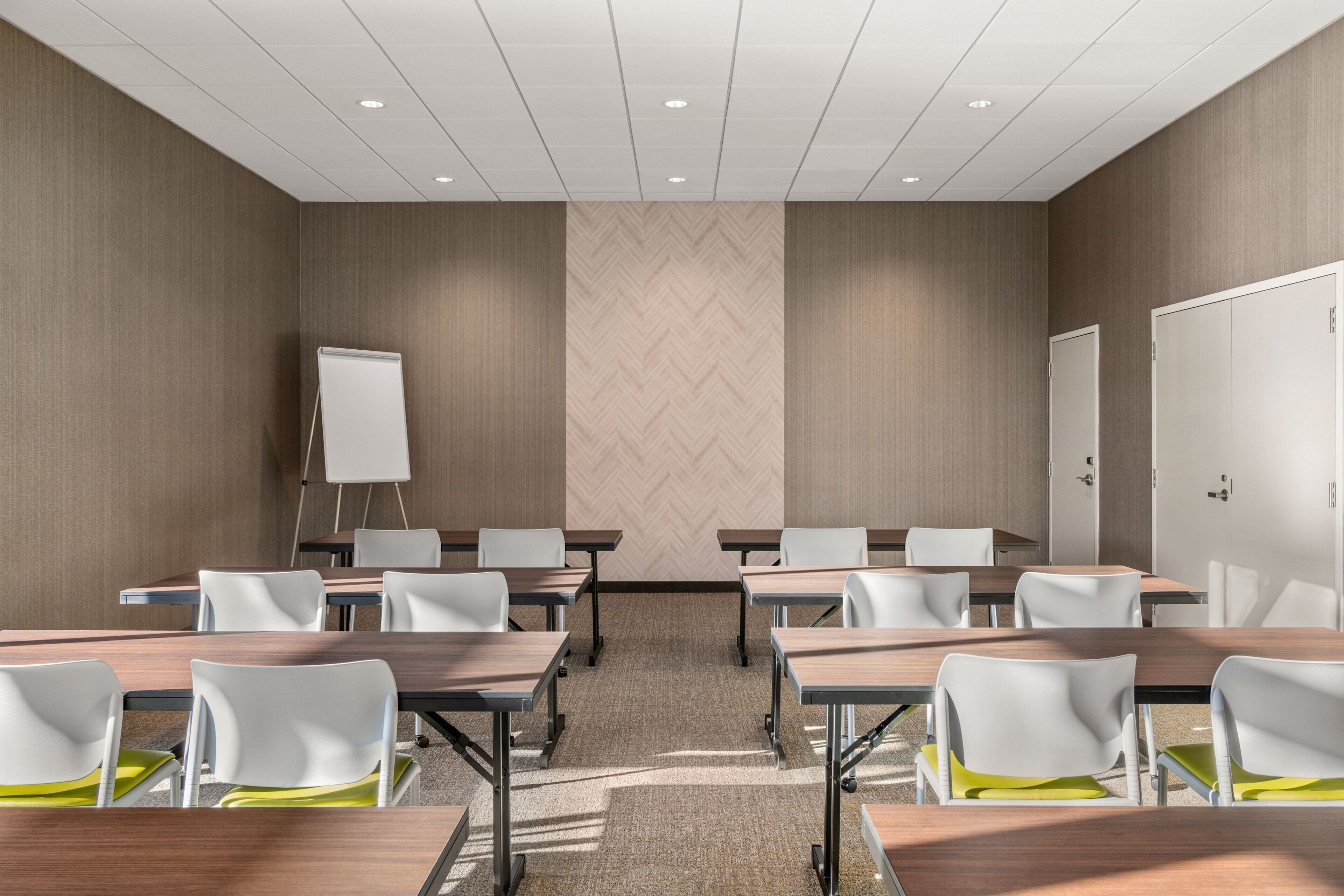 A conference room with a whiteboard, multiple tables, and chairs.