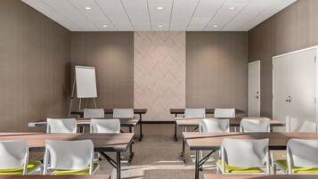 A conference room with a whiteboard, multiple tables, and chairs.