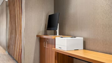 Et moderne kontormiljø med et træskrivebord, en computerskærm og en printer.
