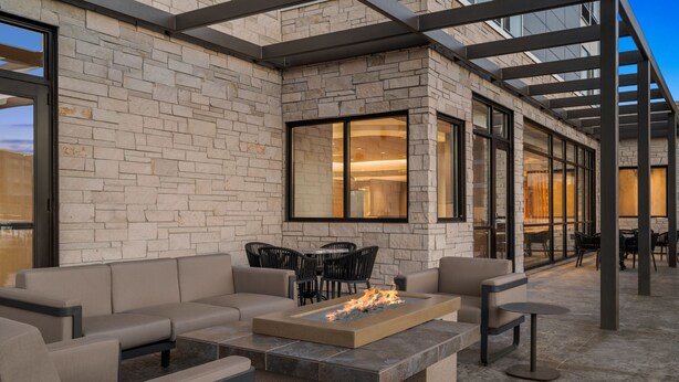 Un patio al aire libre con chimenea, asientos y una pared de piedra.