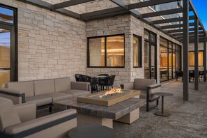 An outdoor patio with a fire feature, seating, and a stone wall.