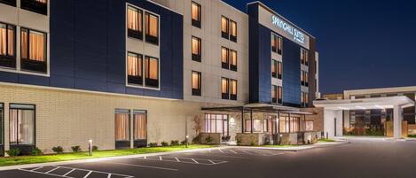 A modern hotel with a large parking lot, a covered entrance, and a sign reading "Springhill Suites by Wyndham".