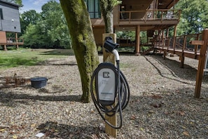An electric vehicle charging station with a wooden post, a cable, and a label indicating it is for electric vehicles.