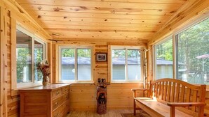 A wooden cabin interior with a wooden bench, a dresser, and a fireplace. - Round Lake Retreat for All Seasons (Park Falls)
