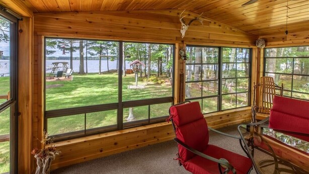 A cabin with large windows offering views of a lake and yard. - Round Lake Retreat for All Seasons (Park Falls)