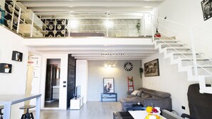 A modern living space with a staircase, a dining area, and a sofa.