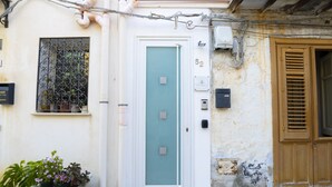 A building with a white door, numbered 52, and a window with metal bars.