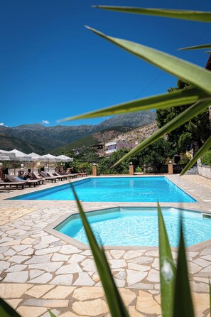 Relax by the pool surrounded by lounge chairs and umbrellas, with breathtaking views of the surrounding mountains.