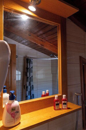 Een badkamer met een houten wastafelmeubel, een spiegel en toiletartikelen op het aanrecht.