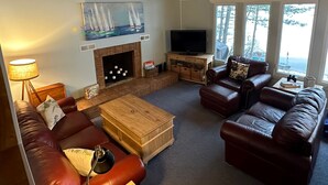 A cozy living room with a fireplace, leather sofas, a coffee table, and a television.