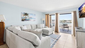 A living room with a sofa, a lamp, a painting, and a view of the outside. - Top Floor at Johns Pass | BP #502 (Madeira Beach)
