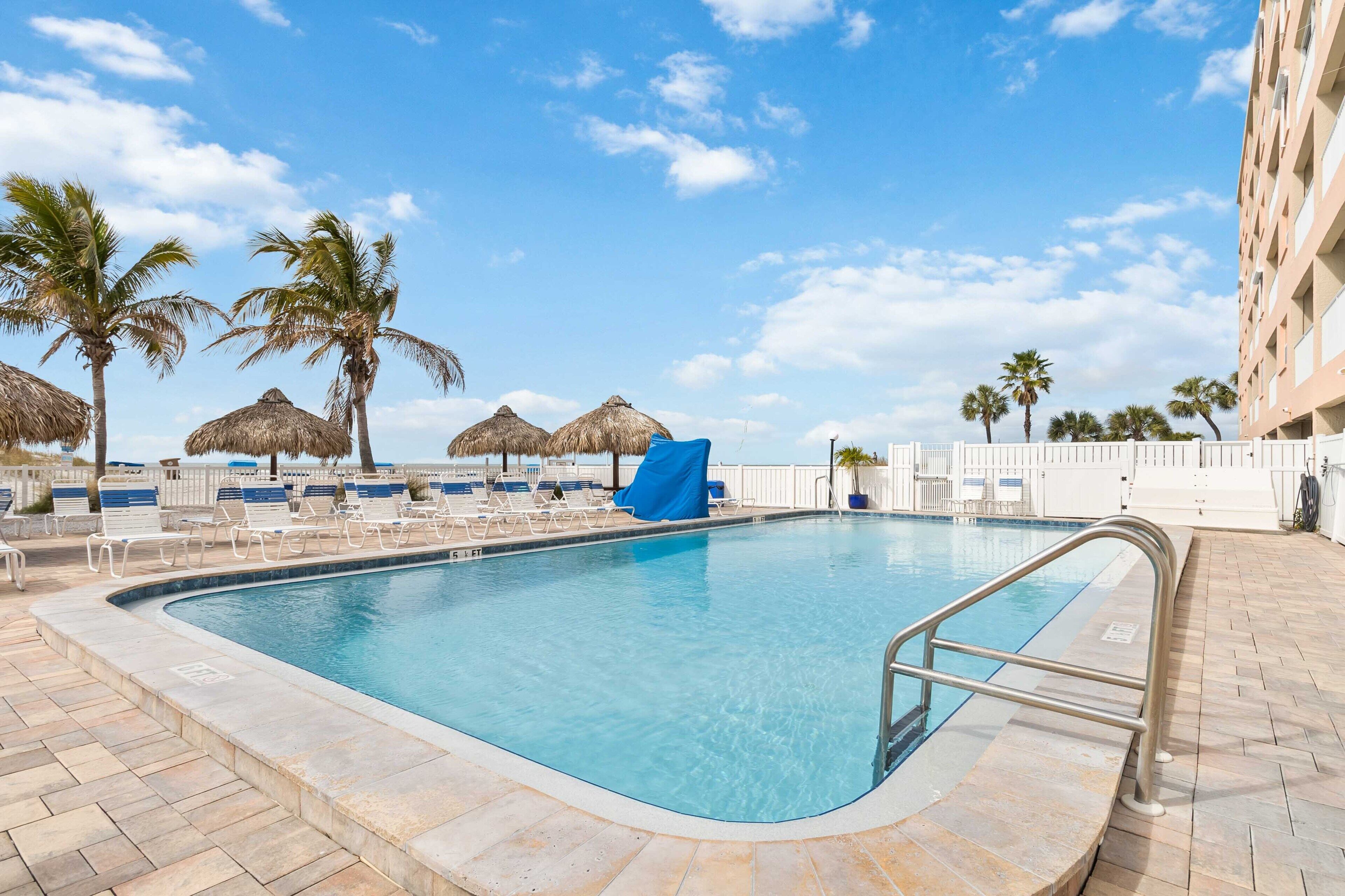 Ein Swimmingpool mit Liegestühlen und Palmen.