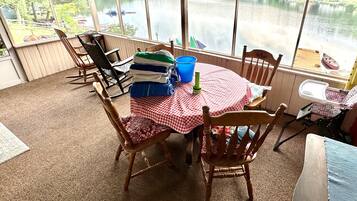 Una habitación con vista a un lago, una mesa con mantel a cuadros y varias sillas.