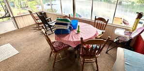 A room with a view of a lake, a table with a checkered tablecloth, and several chairs. - Lake Demmon Lodge-Beach,Boats,Fishing,FUN!! (Bath)