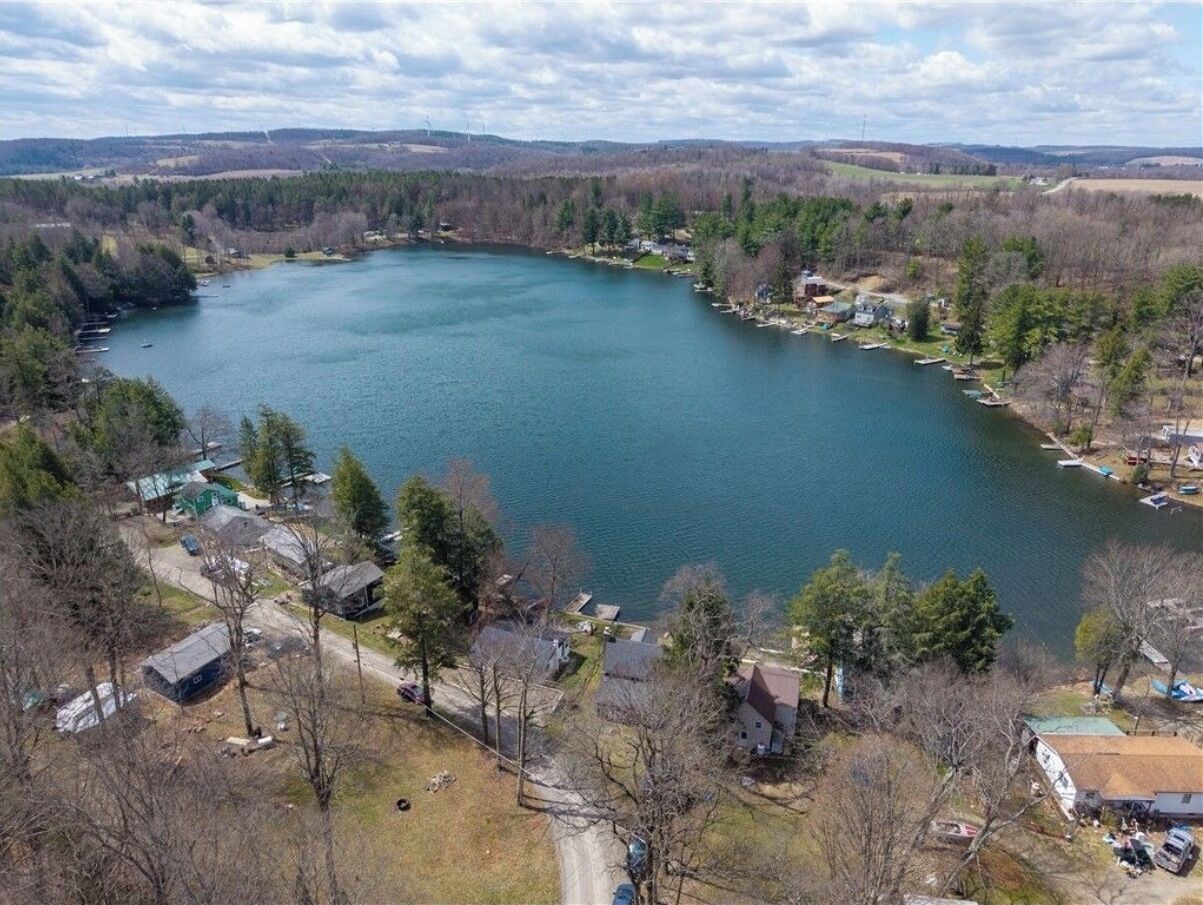 Un lac entouré de maisons avec des quais et des bateaux bien visibles.