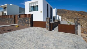 Un edificio moderno con un muro de piedra y un acceso pavimentado.